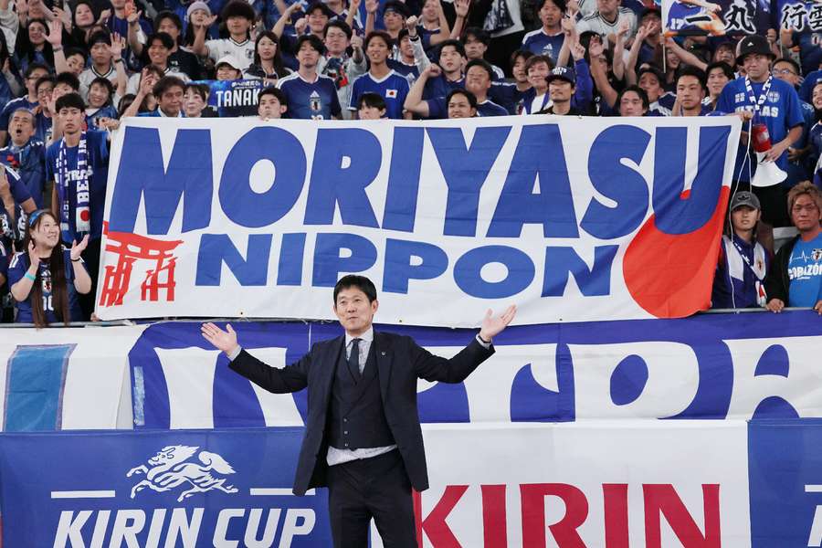 Japan's manager Hajime Moriyasu poses with a banner during the game against New Zealand. Japan's manager Hajime Moriyasu poses with a banner during the game against New Zealand.